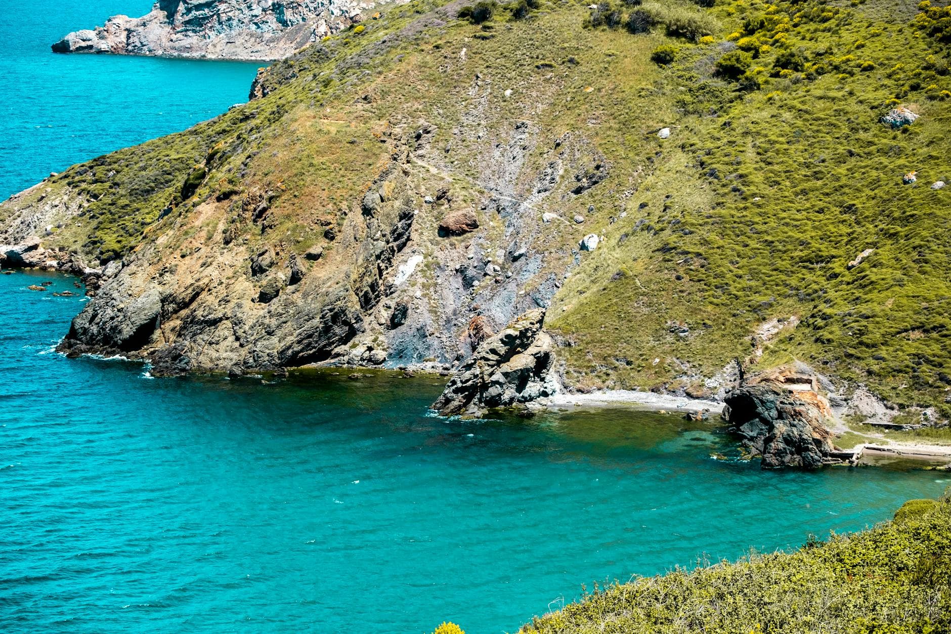 Green rocky hillside trail above the Pacific Ocean