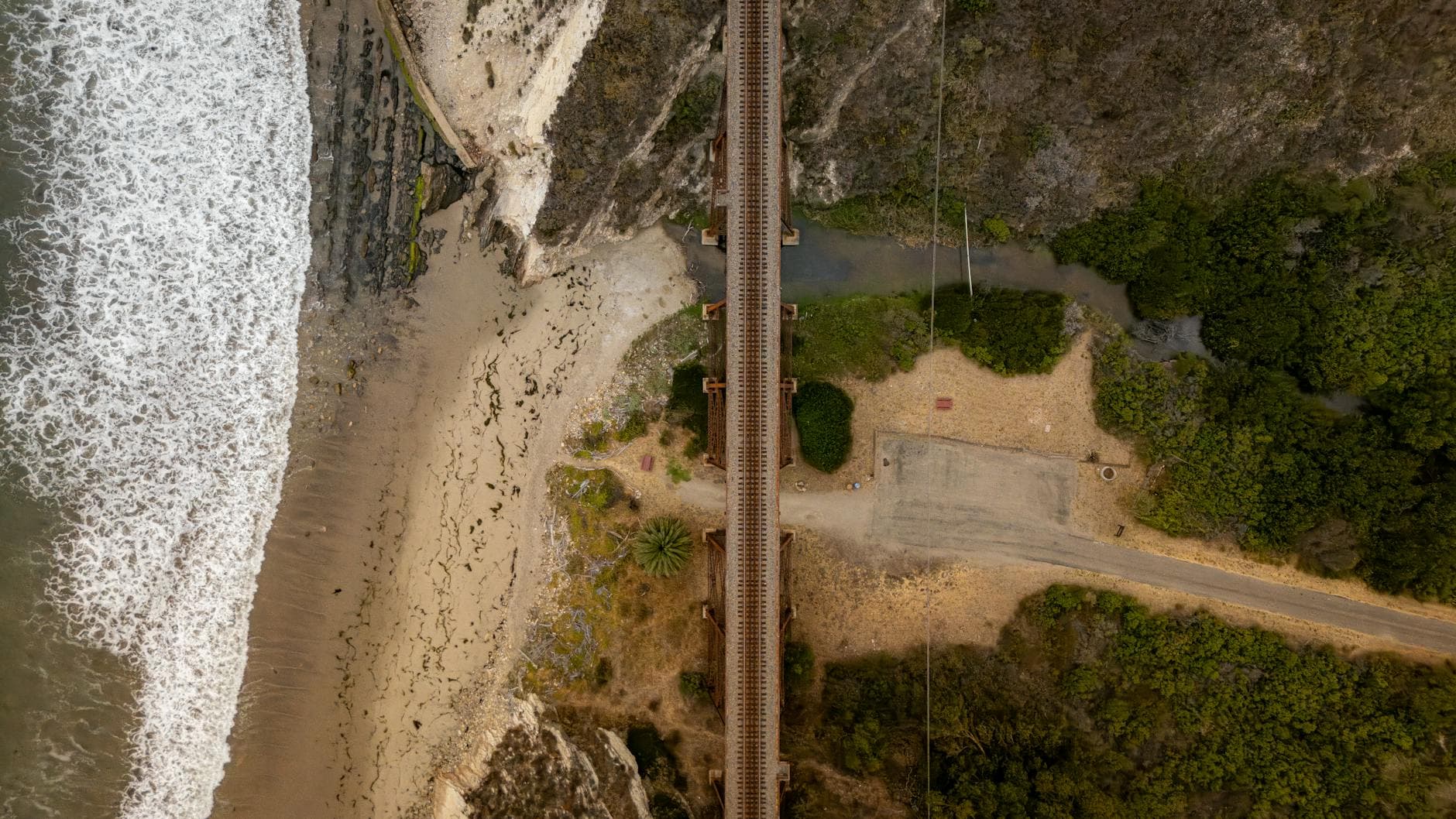 Aerial view of a coastal railway bridge along the California shore