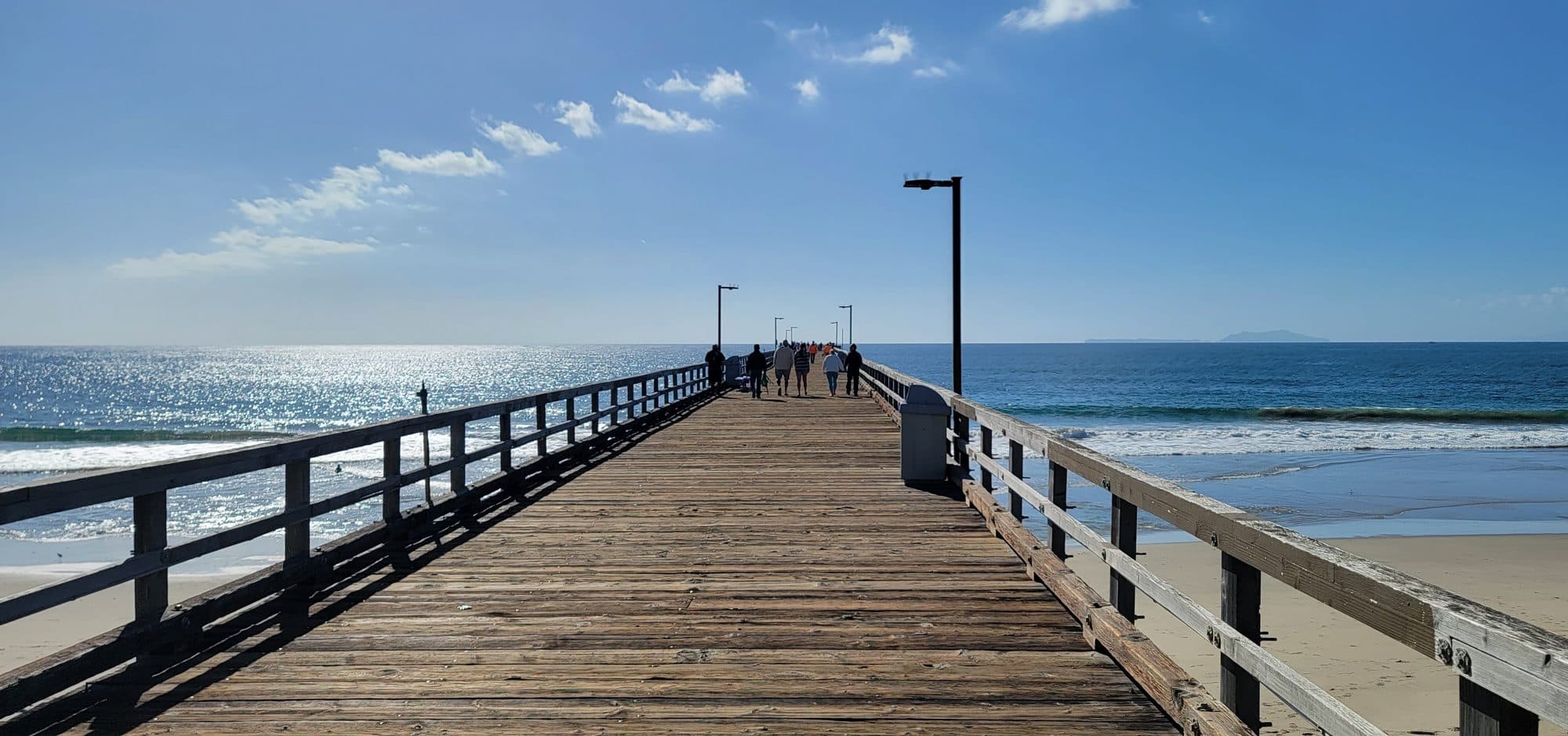 The Hueneme Pier boardwalk on a clear afternoon, with Anacapa Island on the horizon