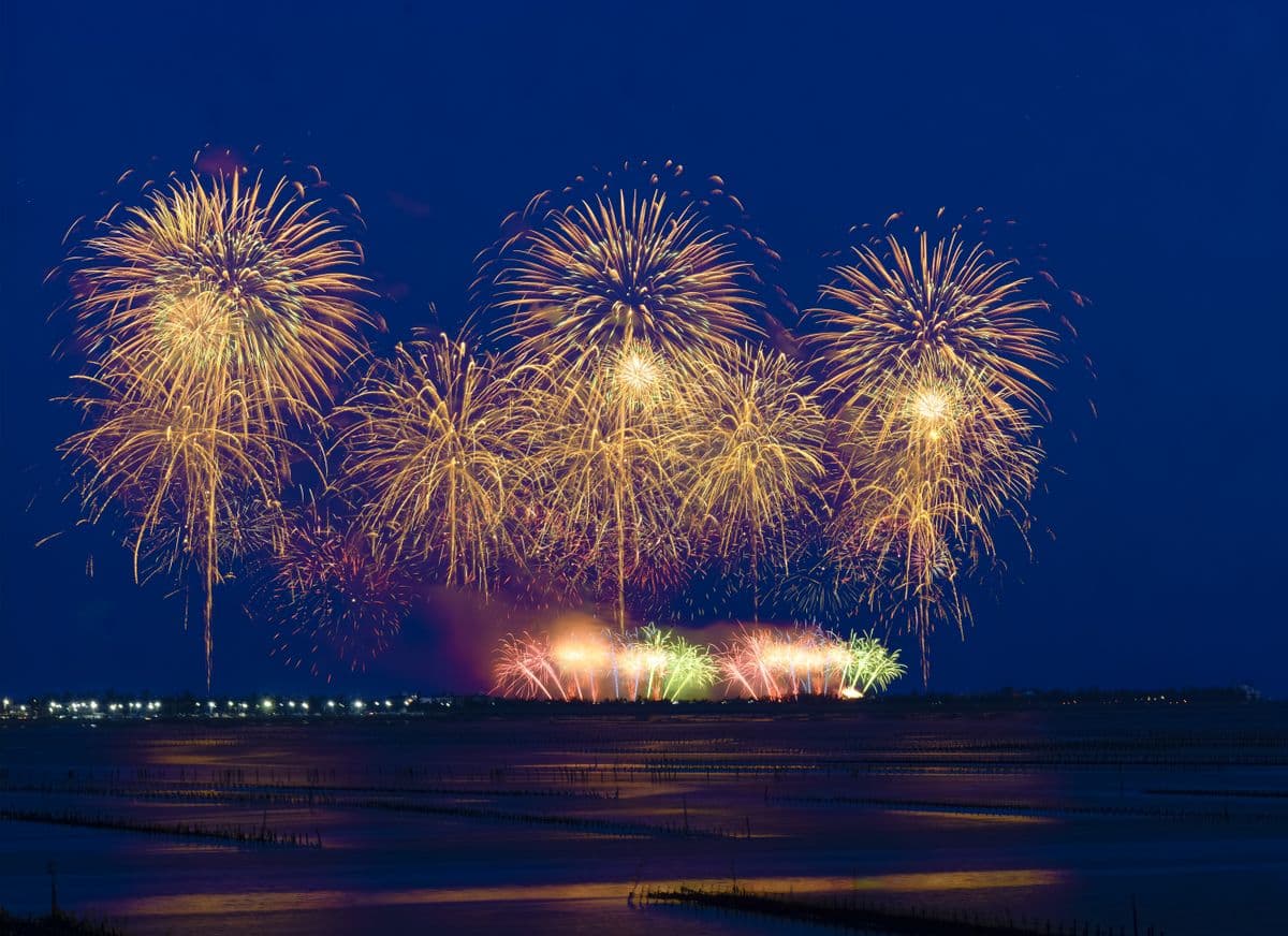 Fireworks reflecting on calm harbor water on the Fourth of July