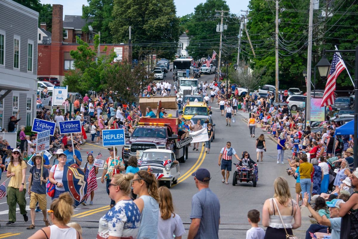 A festive Fourth of July street parade with floats and a crowd of spectators