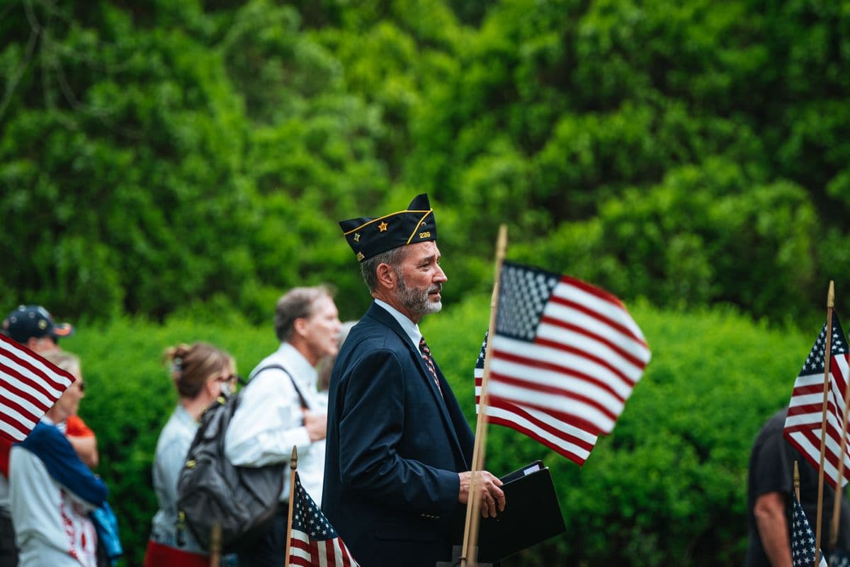 A veteran in uniform among American flags at a patriotic Fourth of July gathering
