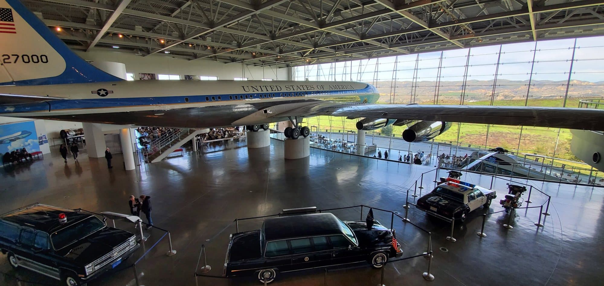 Air Force One and the presidential motorcade cars in the Reagan Library's pavilion in Simi Valley, with the hills visible through the glass wall