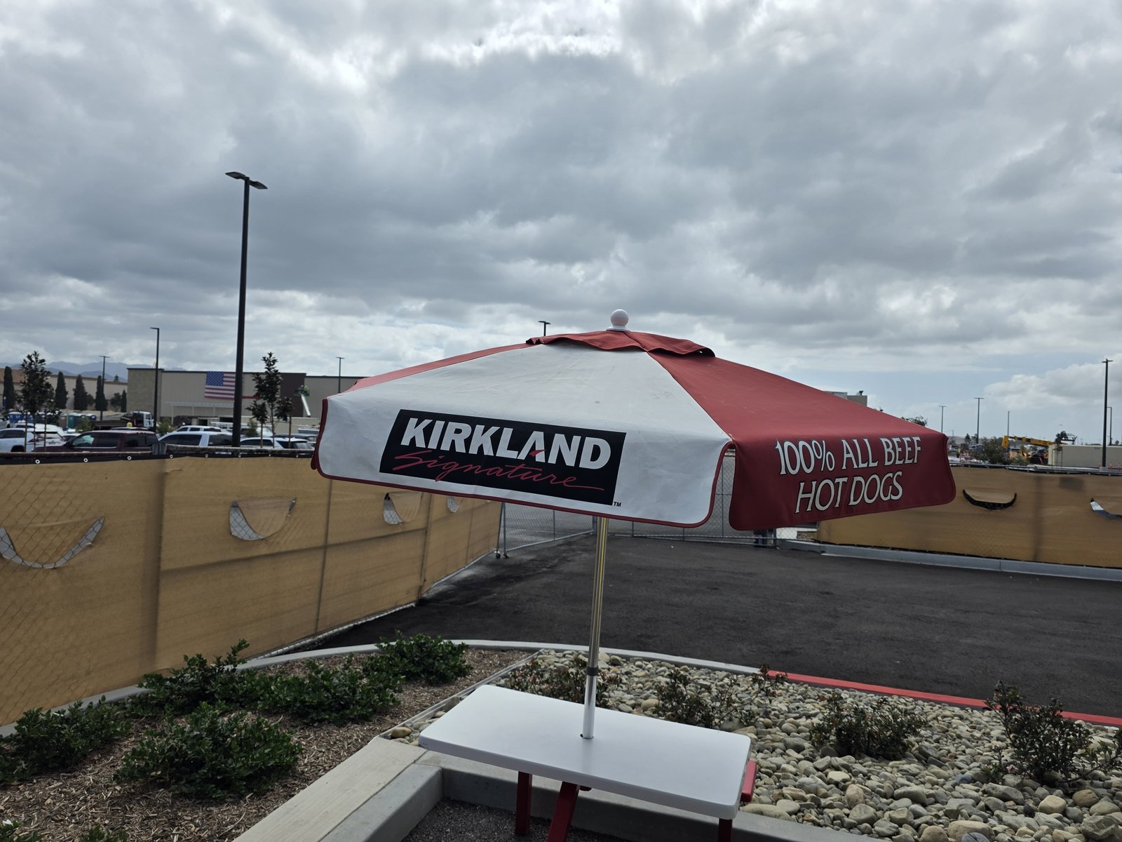 A red and white Kirkland Signature umbrella reading 100% All Beef Hot Dogs over a table at the Camarillo Costco site