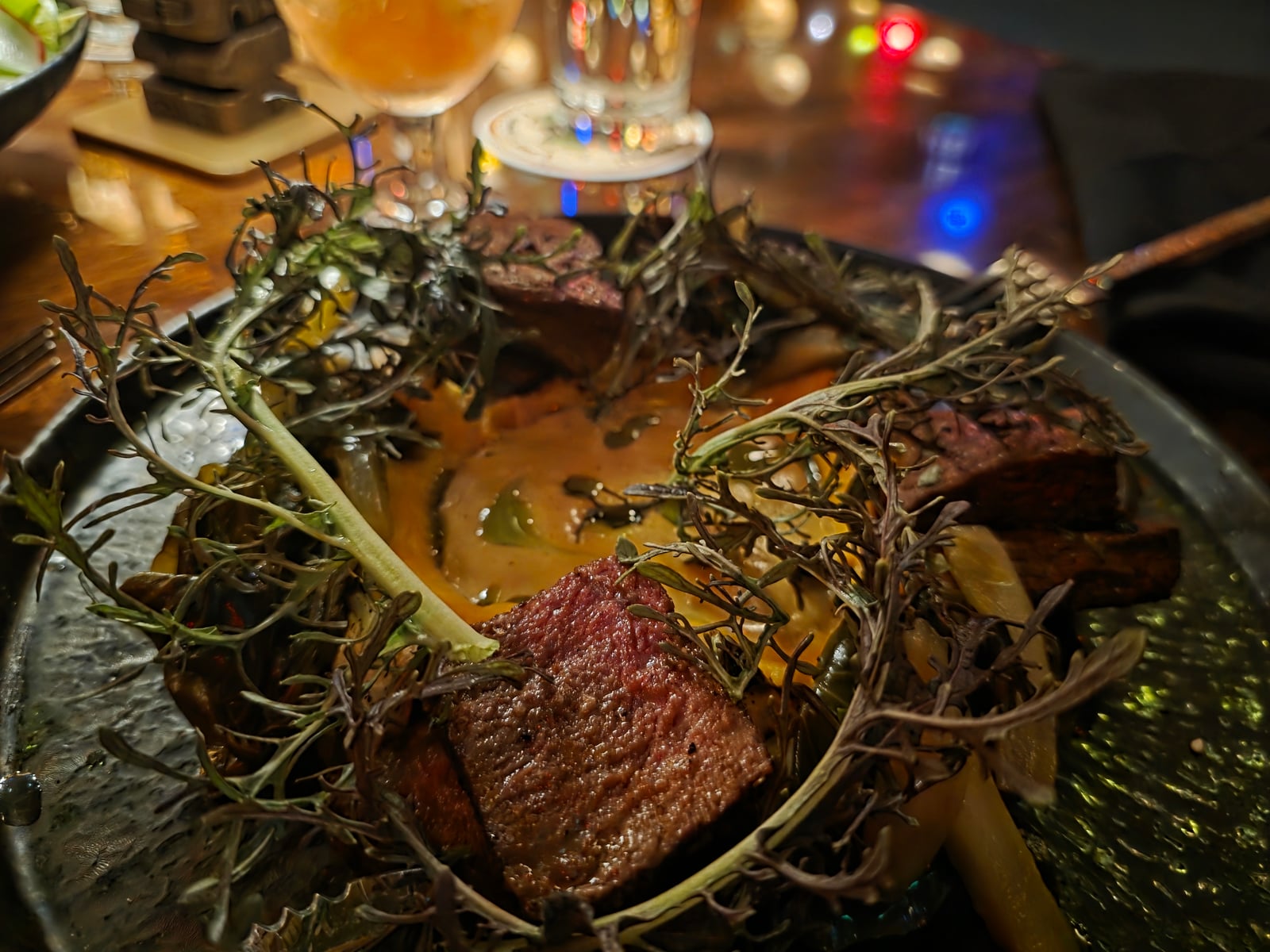 The Coulotte Steak at House of Bamboo, sliced prime coulotte over squash puree and yellow coconut curry, with gai lan and grilled Tokyo turnips, topped with a charred herb bouquet