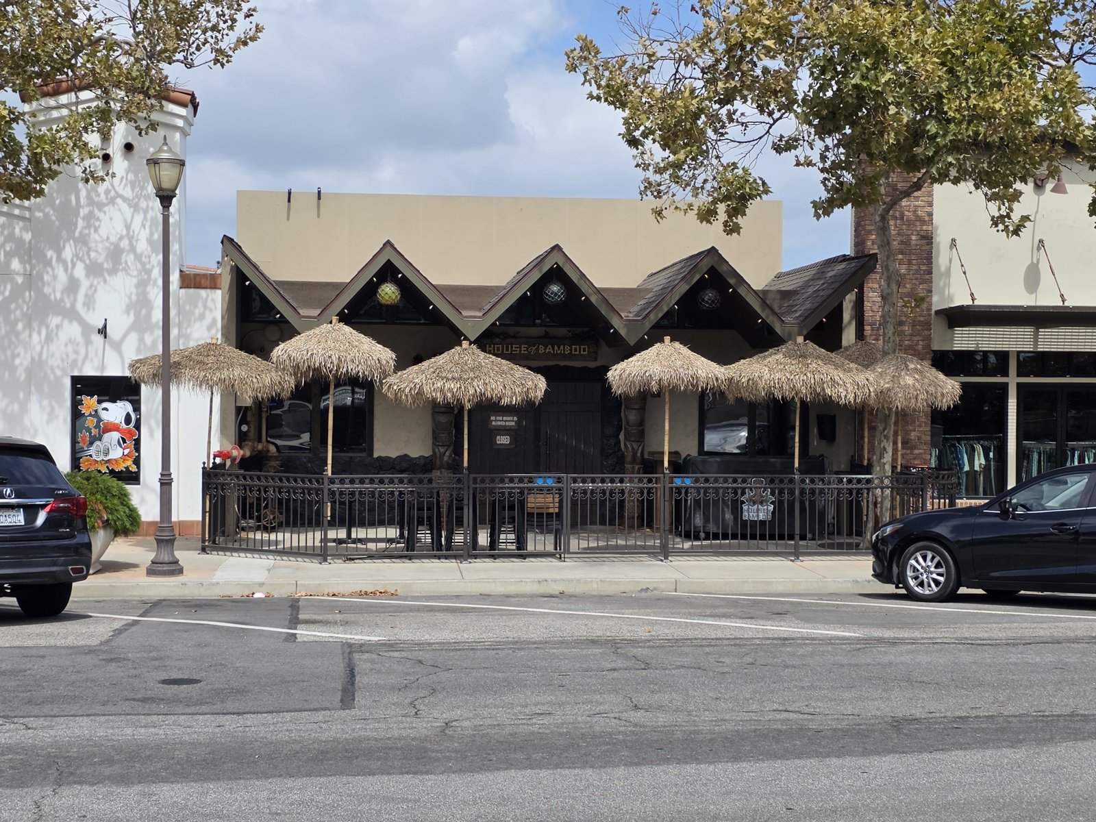 The front patio at House of Bamboo on Ventura Boulevard in Old Town Camarillo, with thatched tiki umbrellas behind a black iron fence