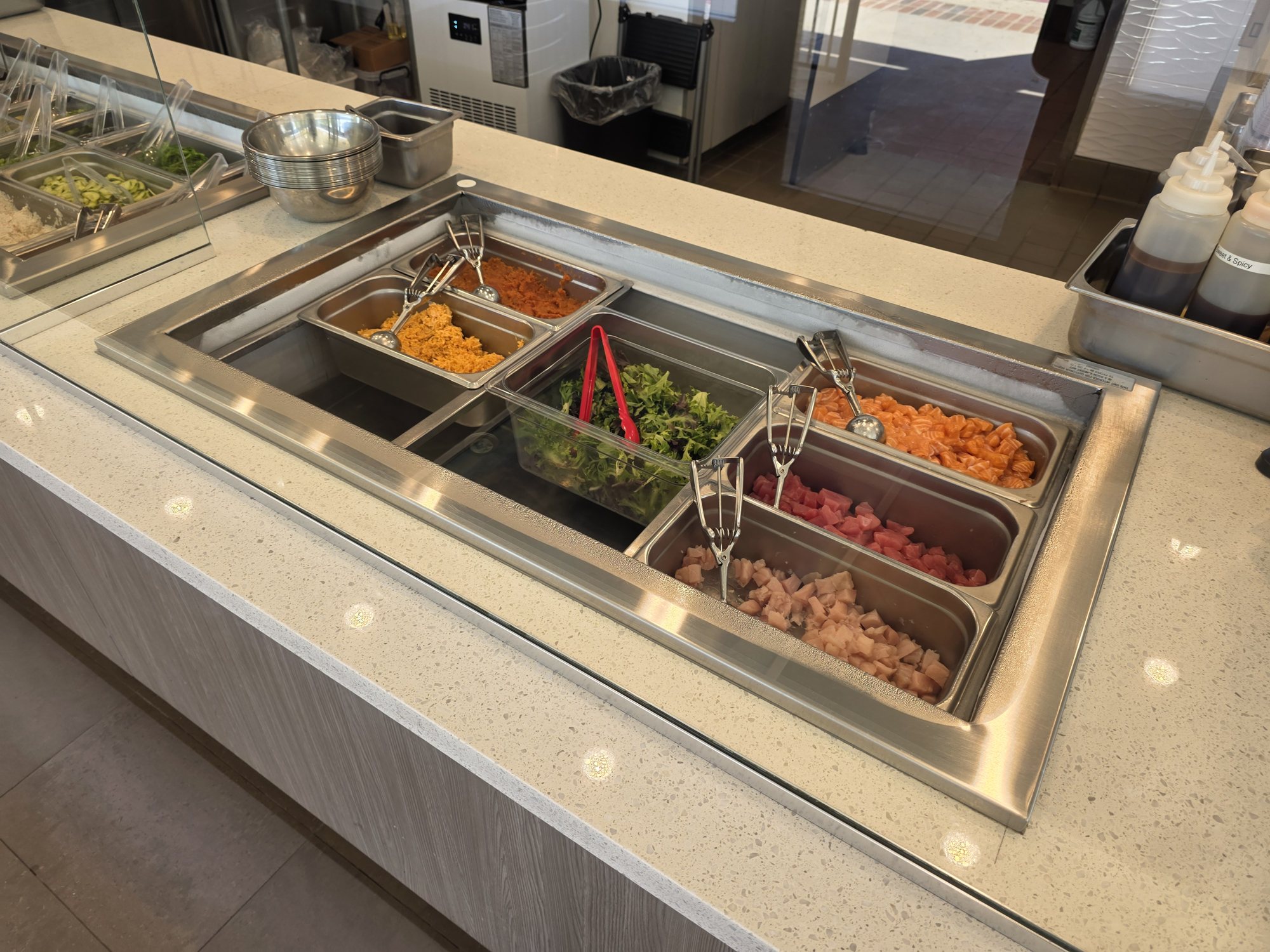 Pans of diced raw fish and seaweed salad in the chilled fish bar at Poke & K-Roll in Camarillo