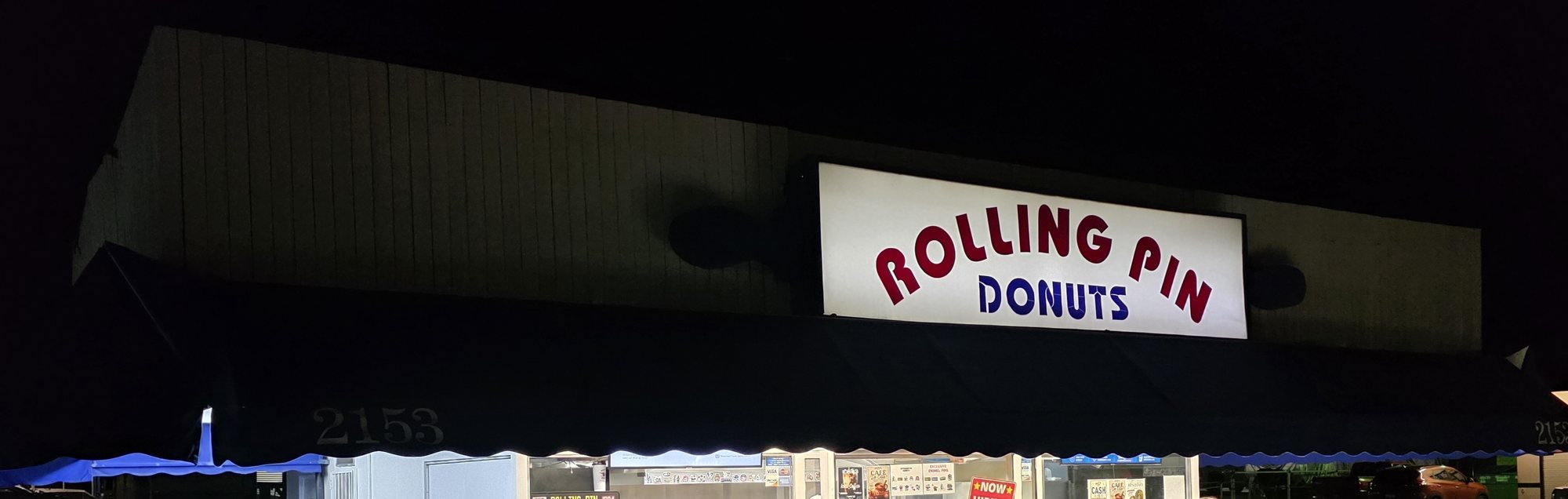 The lit Rolling Pin Donuts sign above the dark awning of the shop at 2153 Las Posas Road in Camarillo at night