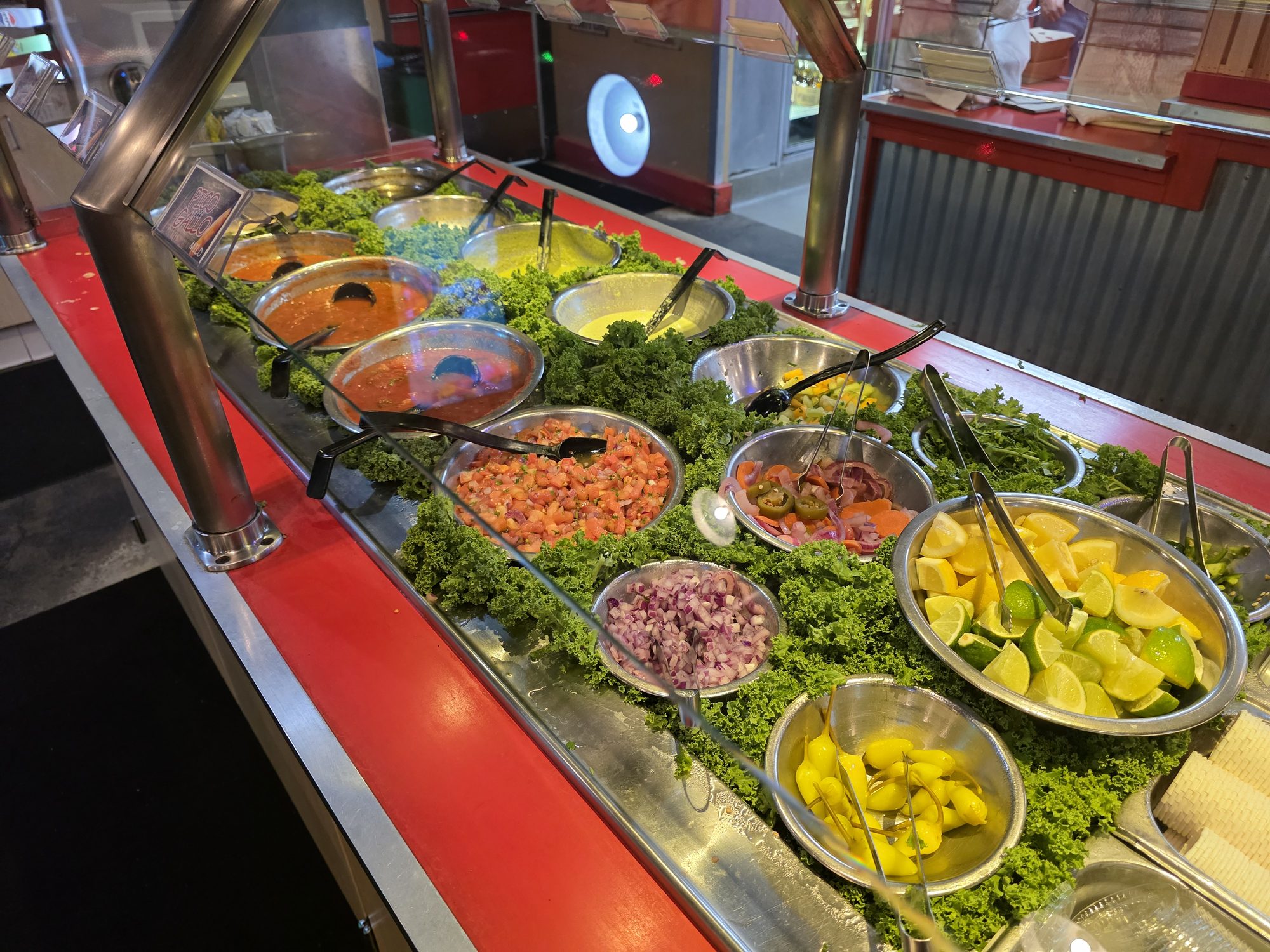 The self-serve salsa bar at Snapper Jack's Taco Shack in Camarillo, with steel bowls of red and green salsa, pico de gallo, lime wedges and pepperoncini on a bed of kale