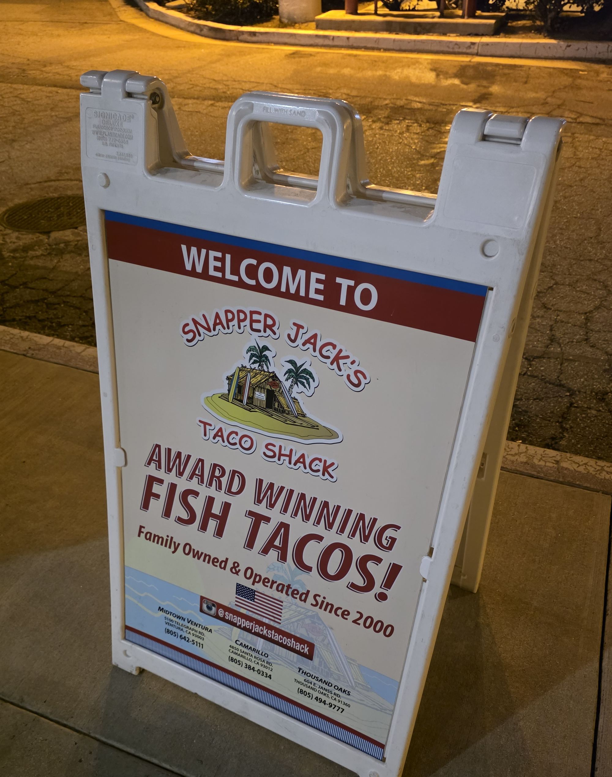 An A-frame sign outside Snapper Jack's Taco Shack in Camarillo reading Award Winning Fish Tacos, Family Owned and Operated Since 2000, with the addresses of the Ventura, Camarillo and Thousand Oaks locations